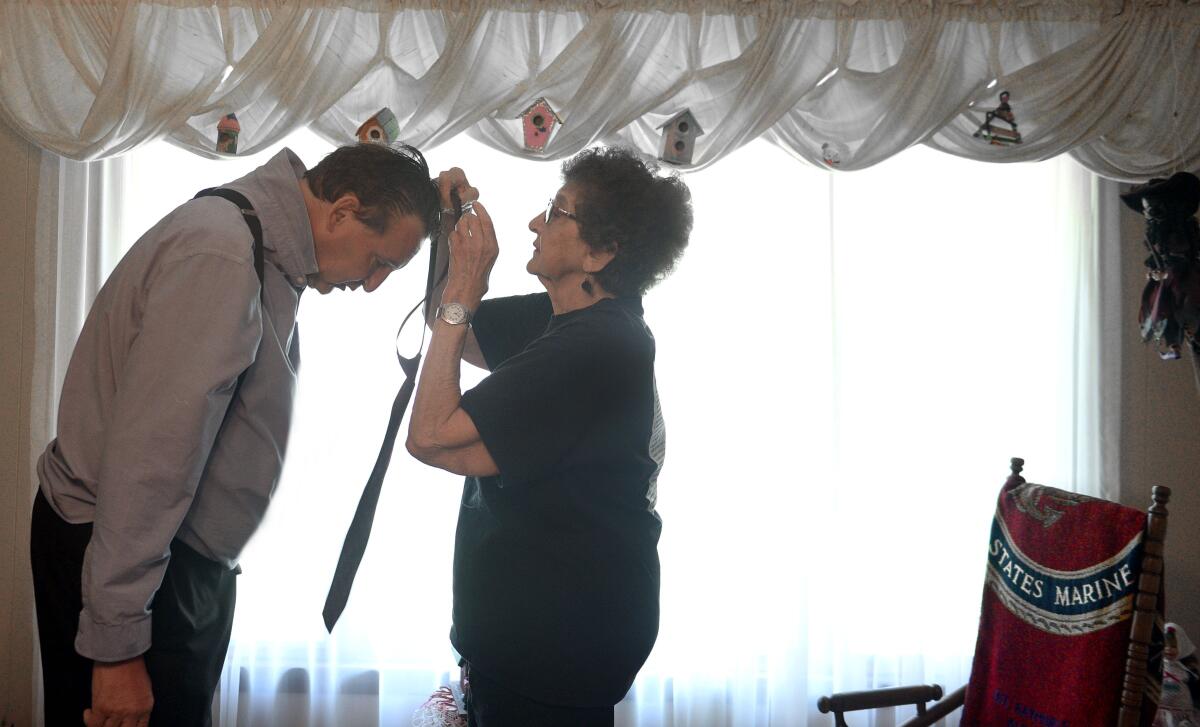 Bill Alkofer gets help dressing from his mother Laura during a visit to North Dakota.