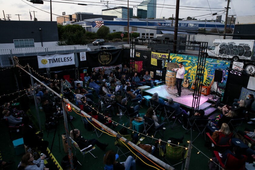 An outdoor stage in a parking lot packed with comedy fans