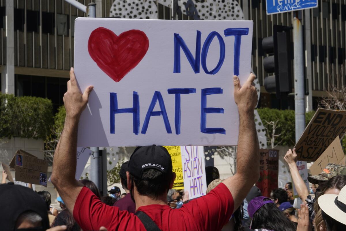 A rally against anti-Asian hate crimes. A person holds a sign saying heart not hate.