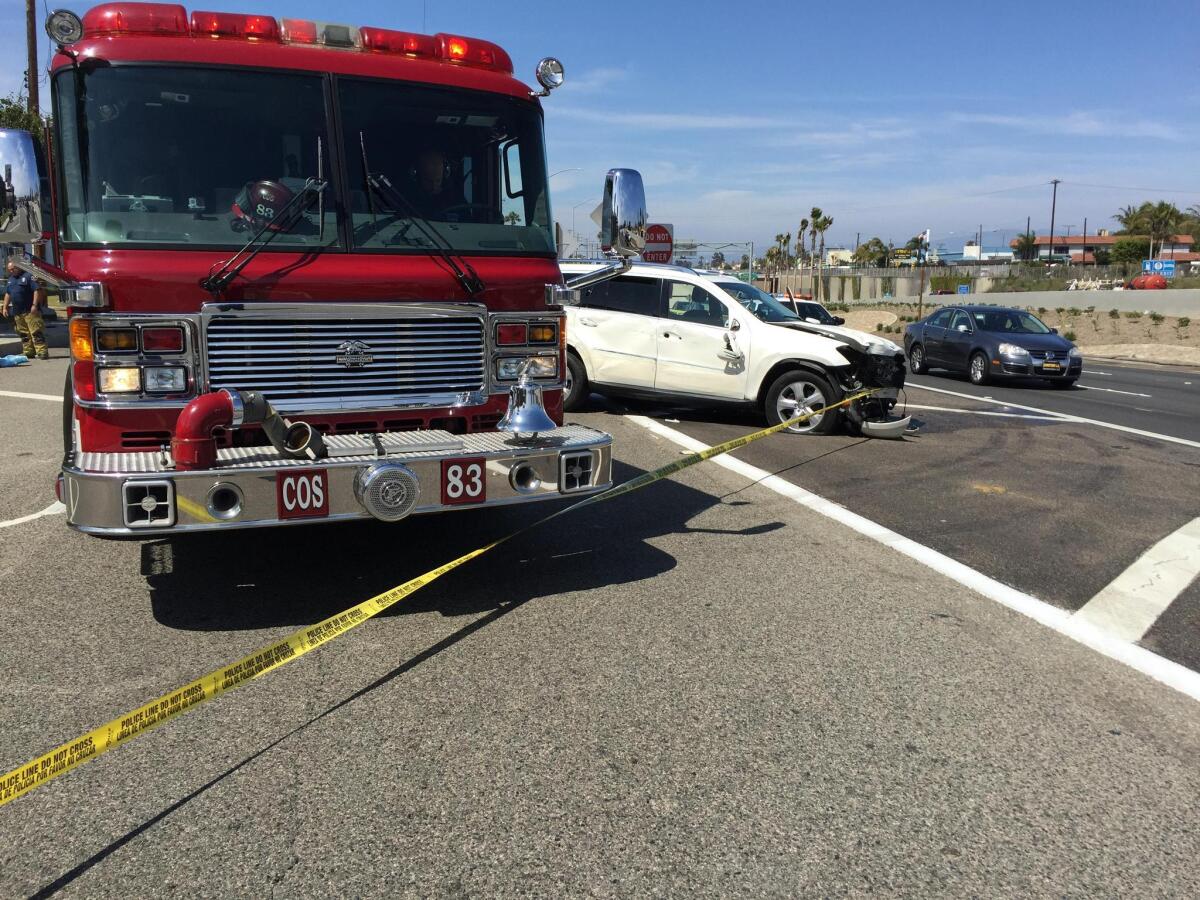 A white Mercedes-Benz SUV is stopped on Newport Boulevard in Costa Mesa on Friday afternoon after swerving onto a sidewalk and hitting a pedestrian, along with a light pole and a bus bench.