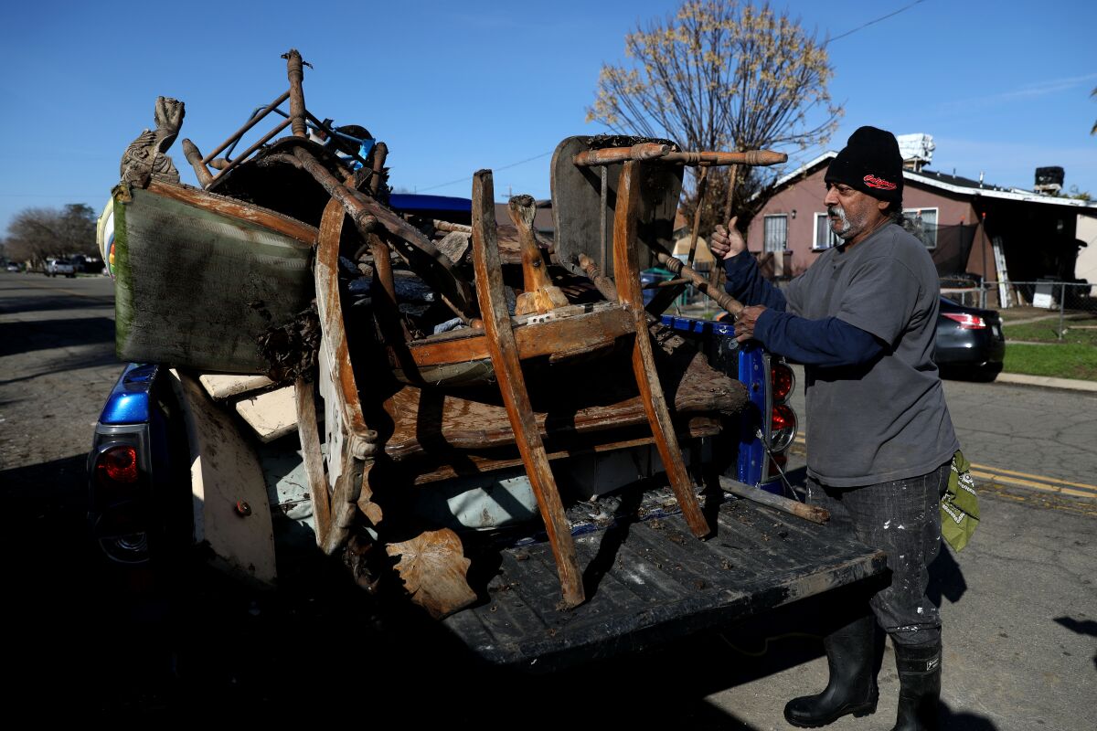 A man lifts damaged chairs into the back of a pickup truck