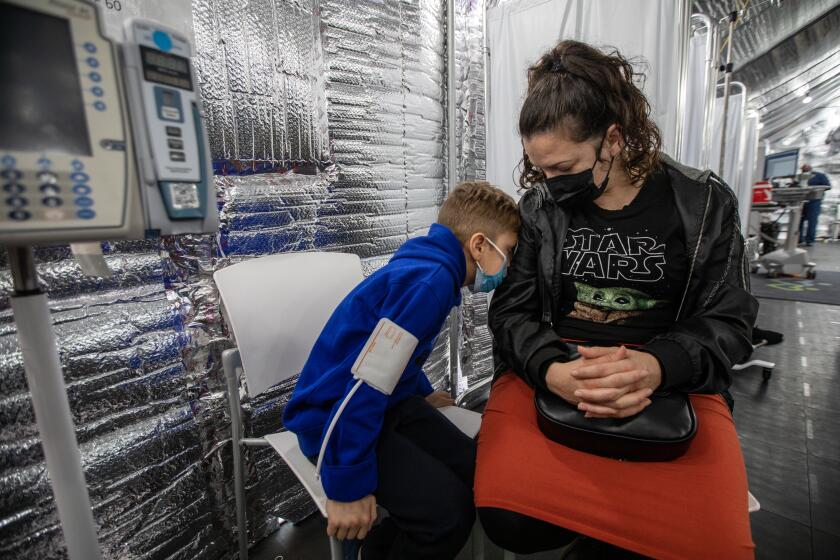 Los Angeles, CA - January 02: Esmeralda Avendano, right, sits with her son Xavier Gomez, 9, left, inside a tent outside the Emergency Department at MLK Community Hospital on Monday, Jan. 2, 2023, in Los Angeles, CA. (Francine Orr / Los Angeles Times)