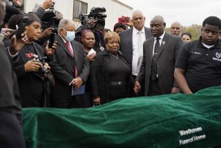 FILE - Surrounded by family members and holding hands with civil rights attorney Ben Crump, center right, Bettersten Wade, center, mother of Dexter Wade, a 37-year-old man who died after being hit by a Jackson, Miss., police SUV driven by an off-duty officer, watches her son's body transferred to a mortuary transport in Raymond, Miss. Nov. 13, 2023. An independent pathologist says the deceased Mississippi man had a wallet in the front pocket of the jeans he was buried in that contained his home address. Crump says the finding came from Dr. Frank Peretti’s autopsy report. Peretti was hired to perform an autopsy after Wade’s body was exhumed. (AP Photo/Rogelio V. Solis, file)