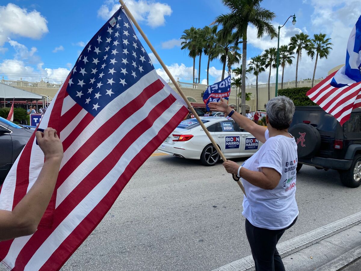 Maria Lourdes Naranjo, waves a American flag at Biden caravan, October 18, in Miami, Fla.