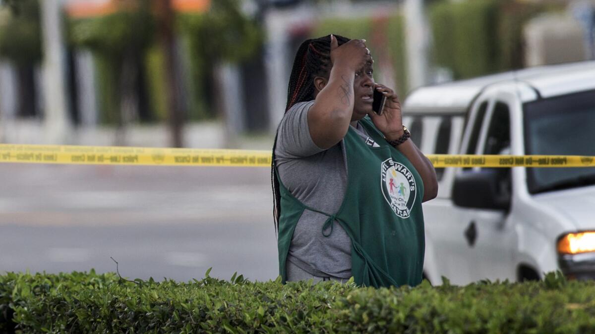 A bystander reacts as she arrives at the scene where three teenagers were shot by a gunman who opened fire and then fled the scene in South Los Angeles.
