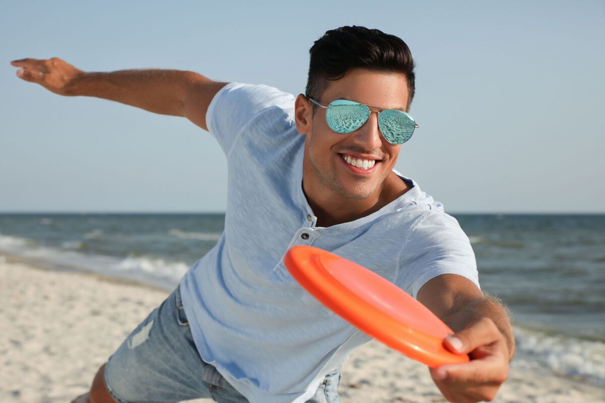 man playing Frisbee at beach