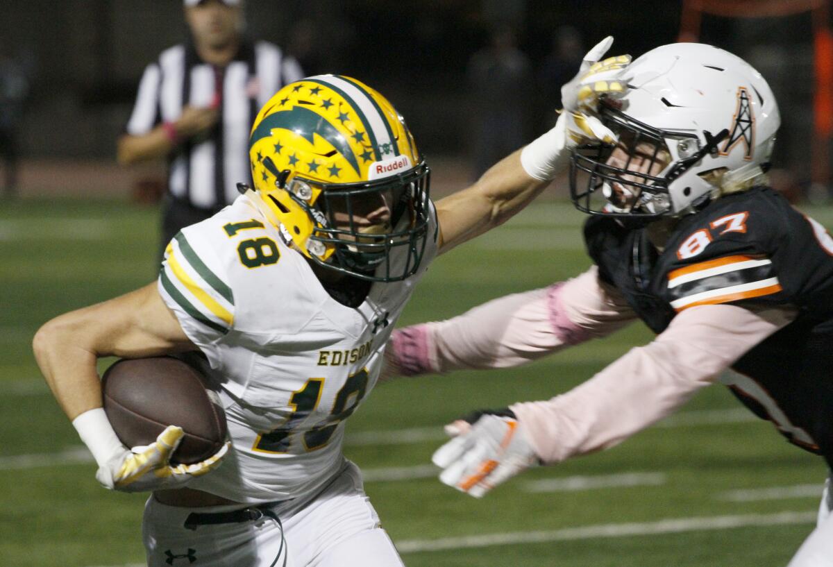 Edison's PJ Campbell stiff-arms Huntington Beach's Brian Reed in a Sunset League game on Friday at Cap Sheue Field.