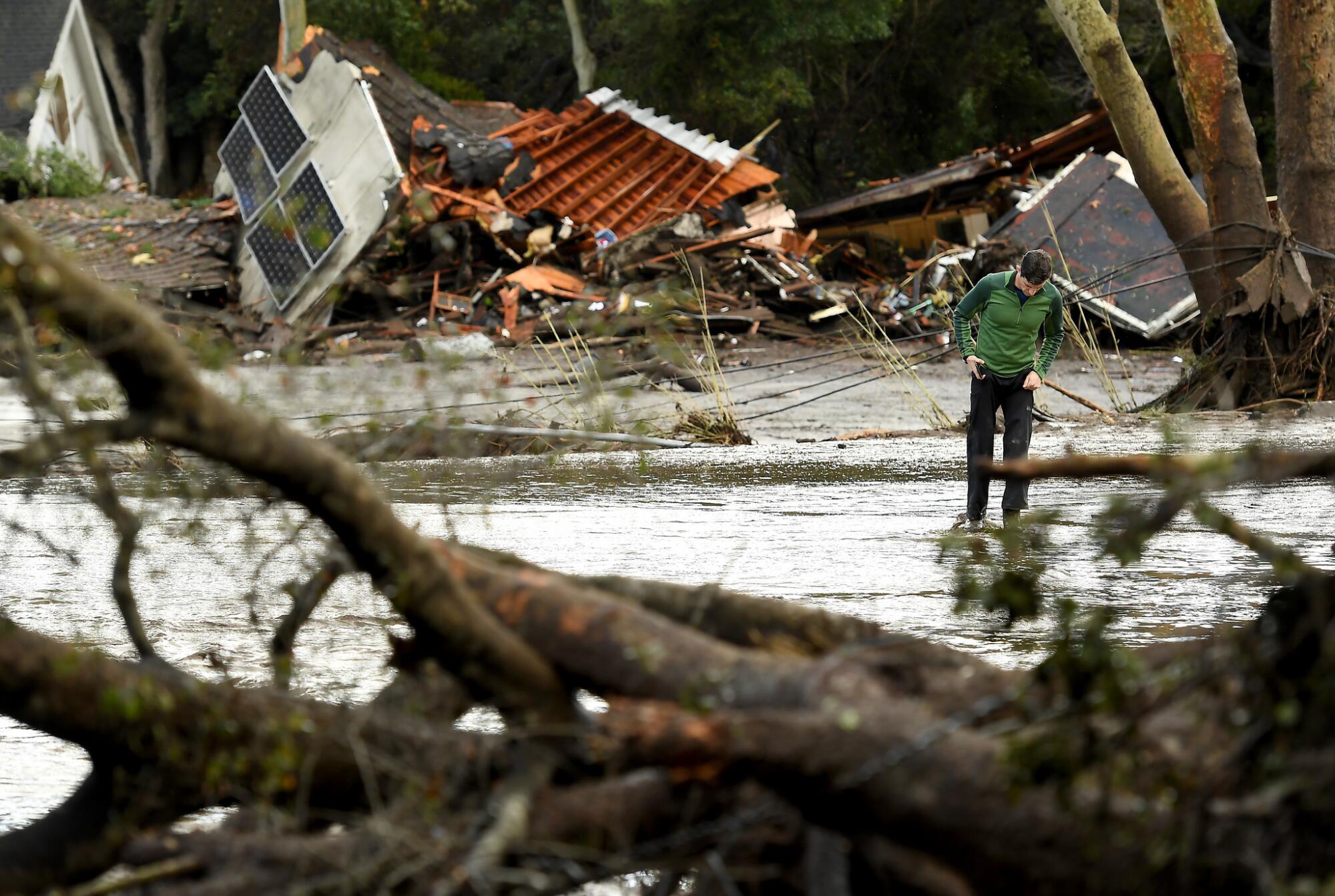 A man walks by destruction from debris flows along Olive Mill Road in Montecito in 2018.