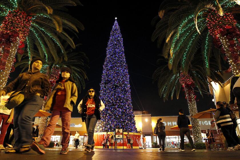 Shoppers pass by a Christmas tree at the Citadel Outlets mall in Los Angeles last year.