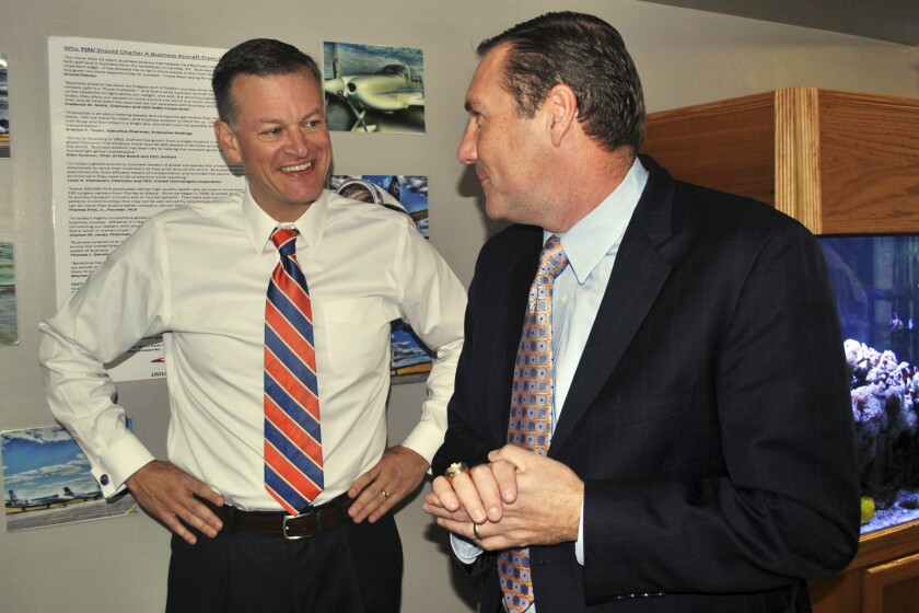 FILE - In this Nov. 27, 2017, file photo, University of Florida athletic director Scott Stricklin, left, smiles as he talks to Florida's new NCAA college football coach Dan Mullen after Mullen arrived at the airport in Gainesville, Fla. Florida’s athletic department had a $54.5 million shortfall during the 2020-21 fiscal year because of the coronavirus pandemic, significant financial losses the Gators were able to weather with a supplement from the Southeastern Conference and a sizeable reserve. (AP Photo/Mark Long, File)