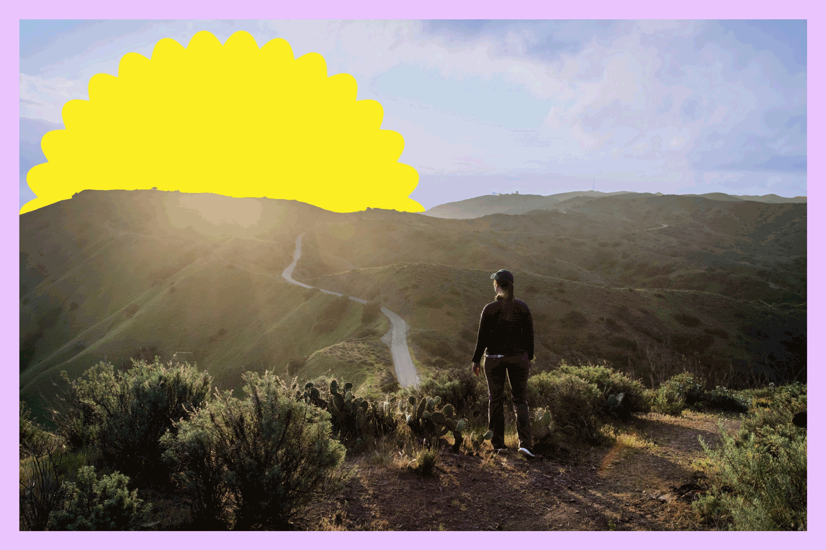A hiker looks at the sunset over a trail and hills.