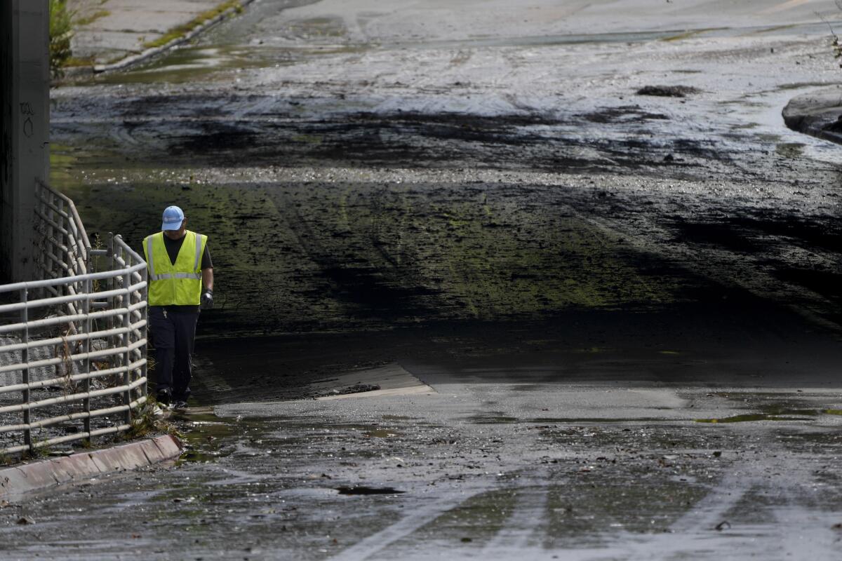 A city worker walks along debris in a road that flooded after the passing of Tropical Storm Hilary.