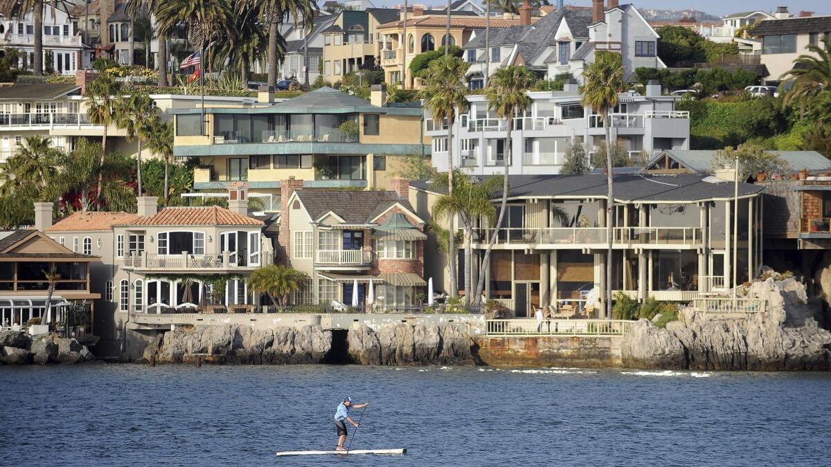 A paddleboard makes his way through the Newport Beach Harbor in Newport Beach, where residents have been complaining about a foul smell in the air.