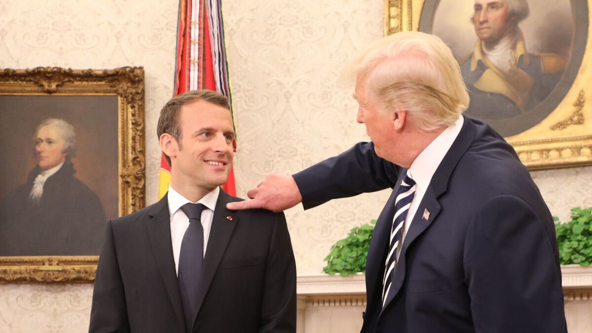 President Trump clears what he referred to as dandruff from French President Emmanuel Macron's jacket in the Oval Office prior to a meeting at the White House.