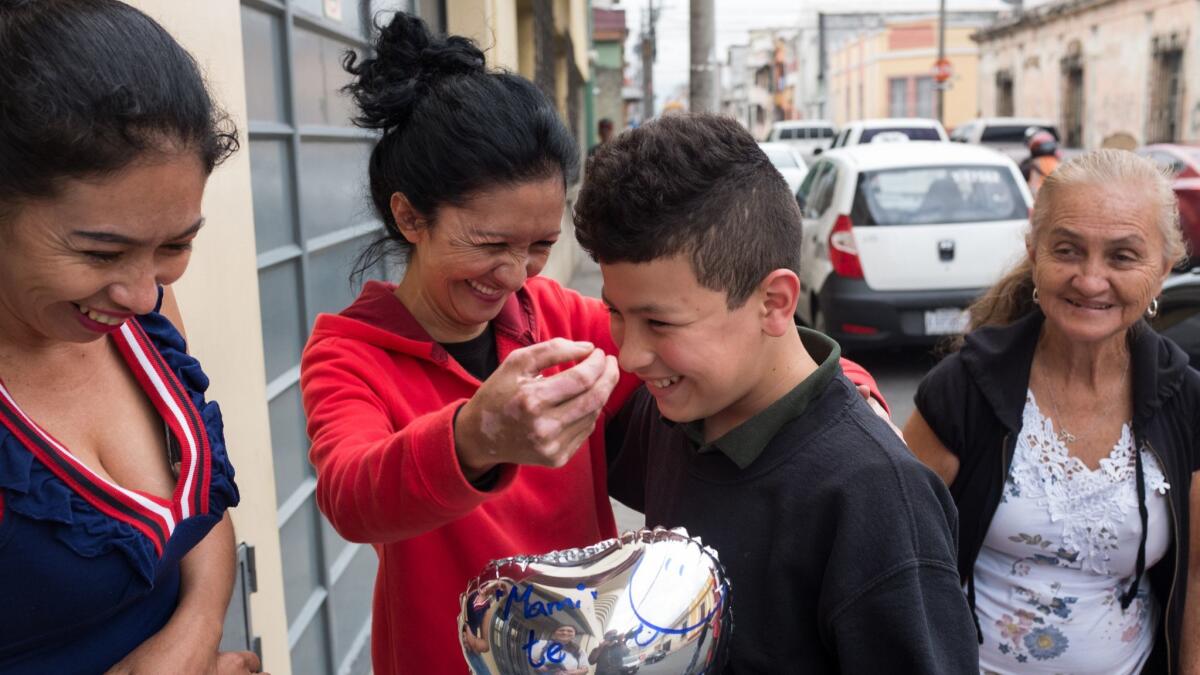 Erik Castillo, 12, smiles as he is greeted by his aunt, center, and his mother and grandmother in Guatemala City, Guatemala.