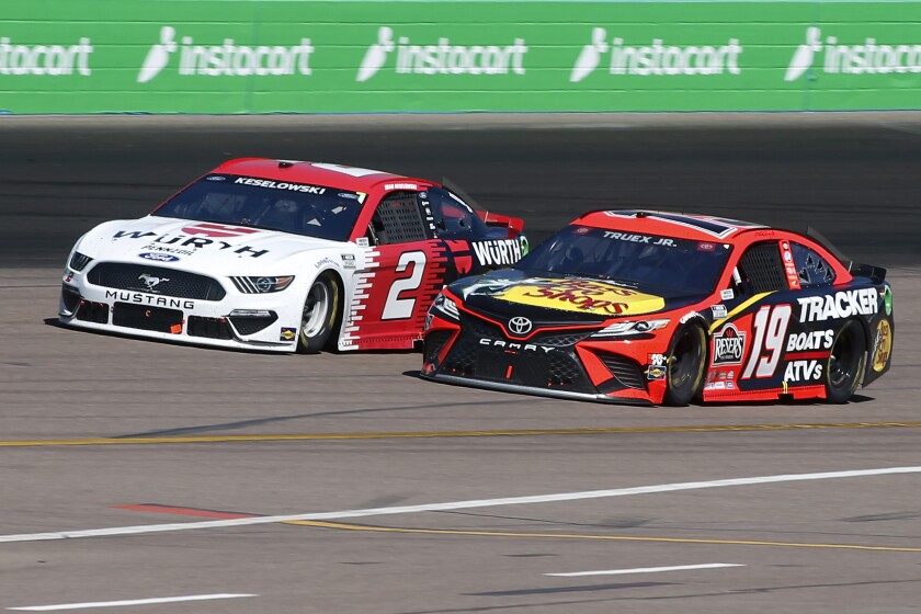 Martin Truex Jr (19) and Brad Keselowski (2) race out of Turn 2 during a NASCAR Cup Series auto race.