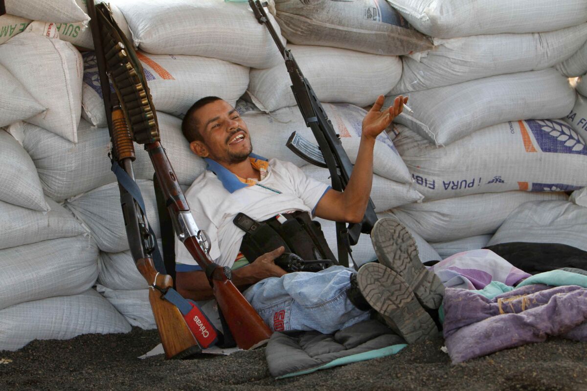 A member of a self-defense group sits behind a barricade at the entrance of Apatzingan in Mexico's Michoacan state in February.