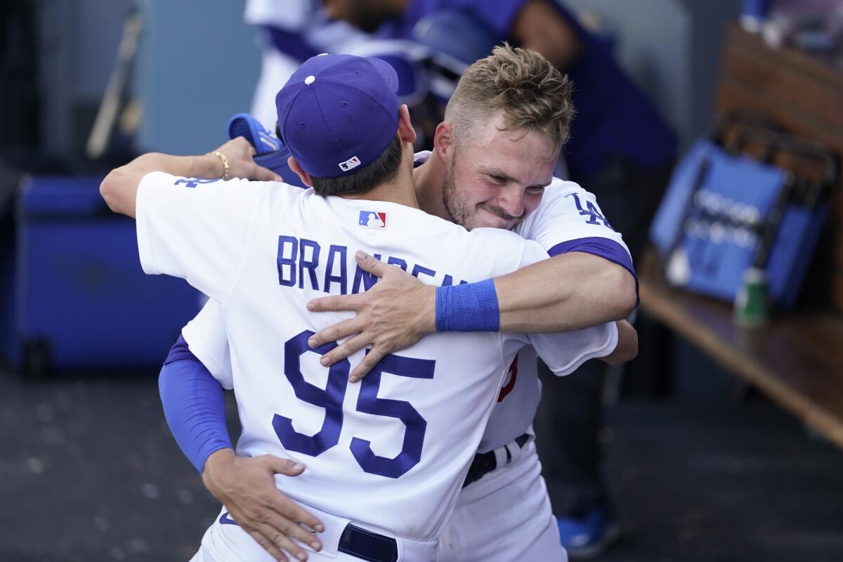 Gavin Lux gets a hug from batboy Branden Vandal in the dugout after the Dodgers' win Sunday.