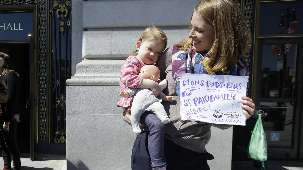 Kim Turner holds her daughter, Adelaide, before a rally at San Francisco City Hall in support of paid family leave.