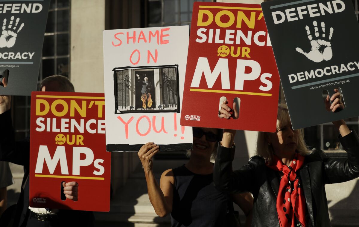 Protesters hold banners outside the Supreme Court in London, Tuesday Sept. 17, 2019. The Supreme Court is set to decide whether Prime Minister Boris Johnson broke the law when he suspended Parliament on Sept. 9, sending lawmakers home until Oct. 14 — just over two weeks before the U.K. is due to leave the European Union. (AP Photo/Matt Dunham)