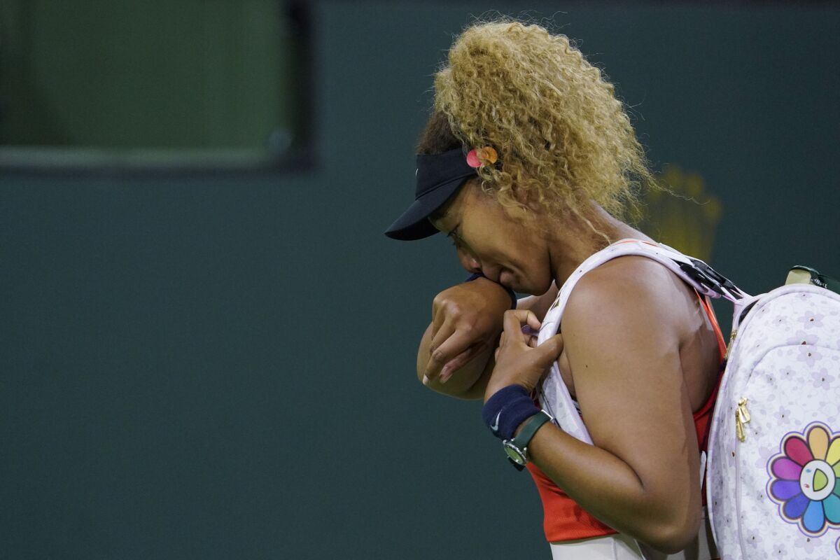 Naomi Osaka wipes away tears as she leaves the court.