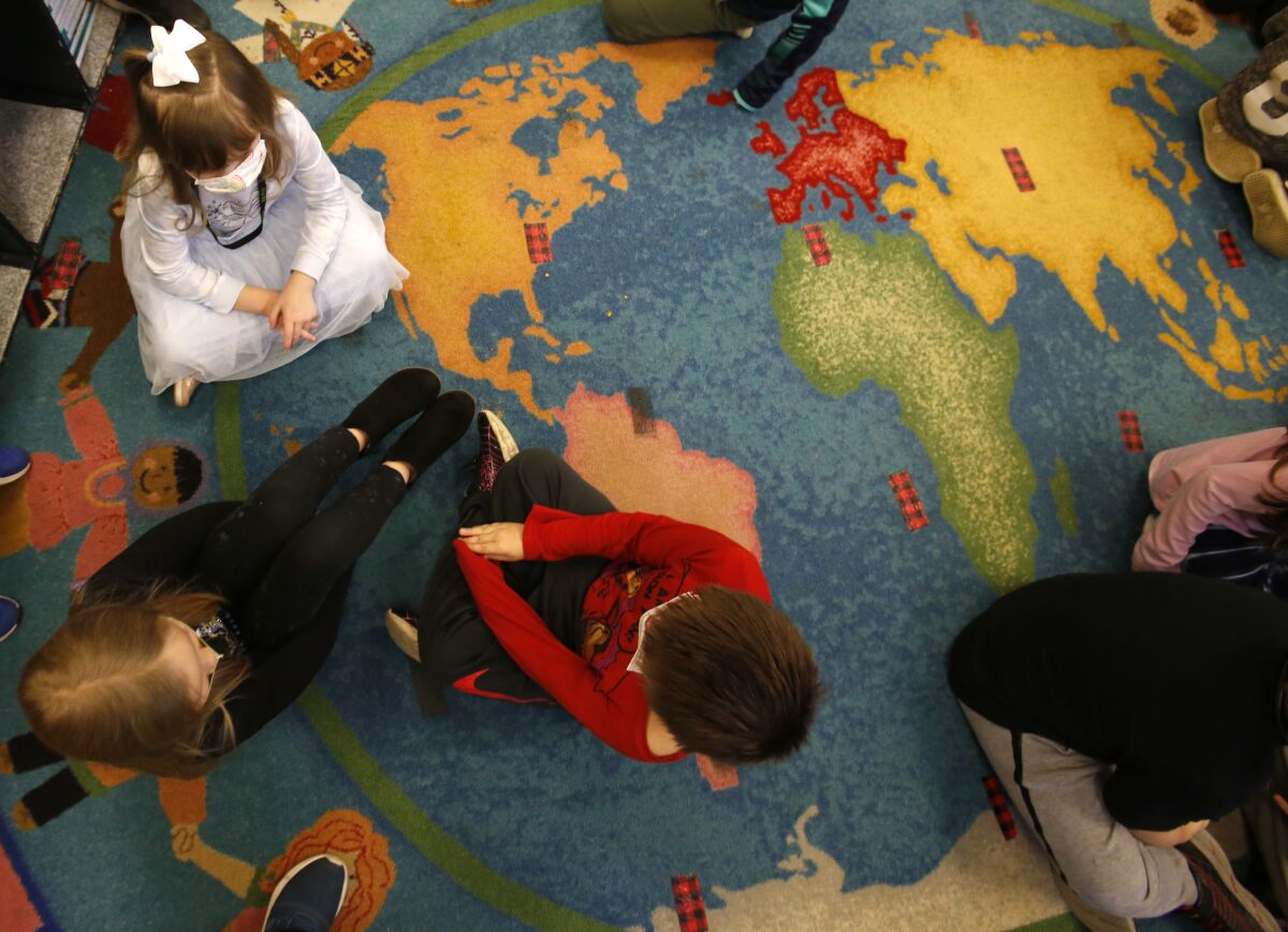 Second-graders sit on the floor and talk.