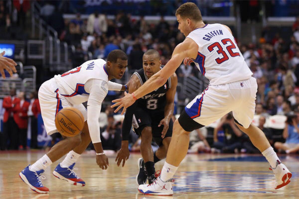 San Antonio's Patty Mills passes the ball between the Clippers' Chris Paul and Blake Griffin -- two of the NBA's highest earning pitchmen -- at Staples Center on Tuesday night.