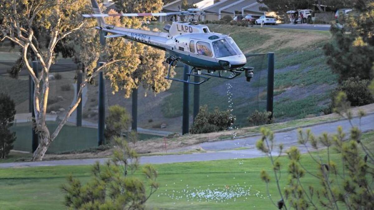 An LAPD helicopter drops golf balls over the course at the La Cañada Flintridge Country Club on Oct. 27. The department is reviewing its use of helicopters for such events after inquiries from The Times.