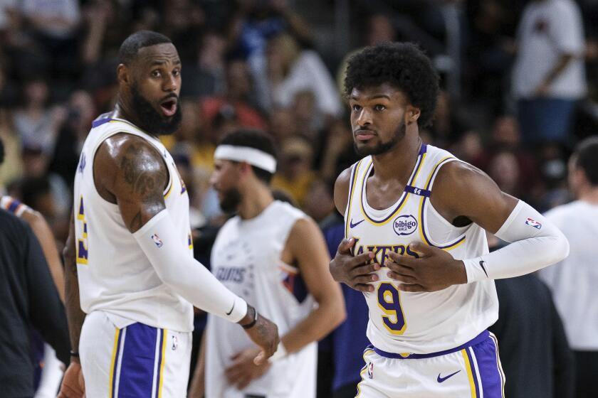 Bronny James (9), derecha, de los Lakers de Los Ángeles, entra a la cancha con su padre LeBron James (23), durante la primera mitad de un partido de pretemporada de baloncesto de la NBA el domingo 6 de octubre de 2024, en Palm Desert, California (Foto AP/William Liang)