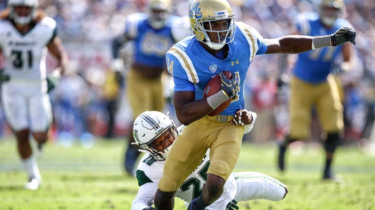 UCLA receiver Theo Howard slips the tackle of Hawaii defensive back Zach Wilson during a second quarter touchdown drive at the Rose Bowl on Sept. 9.