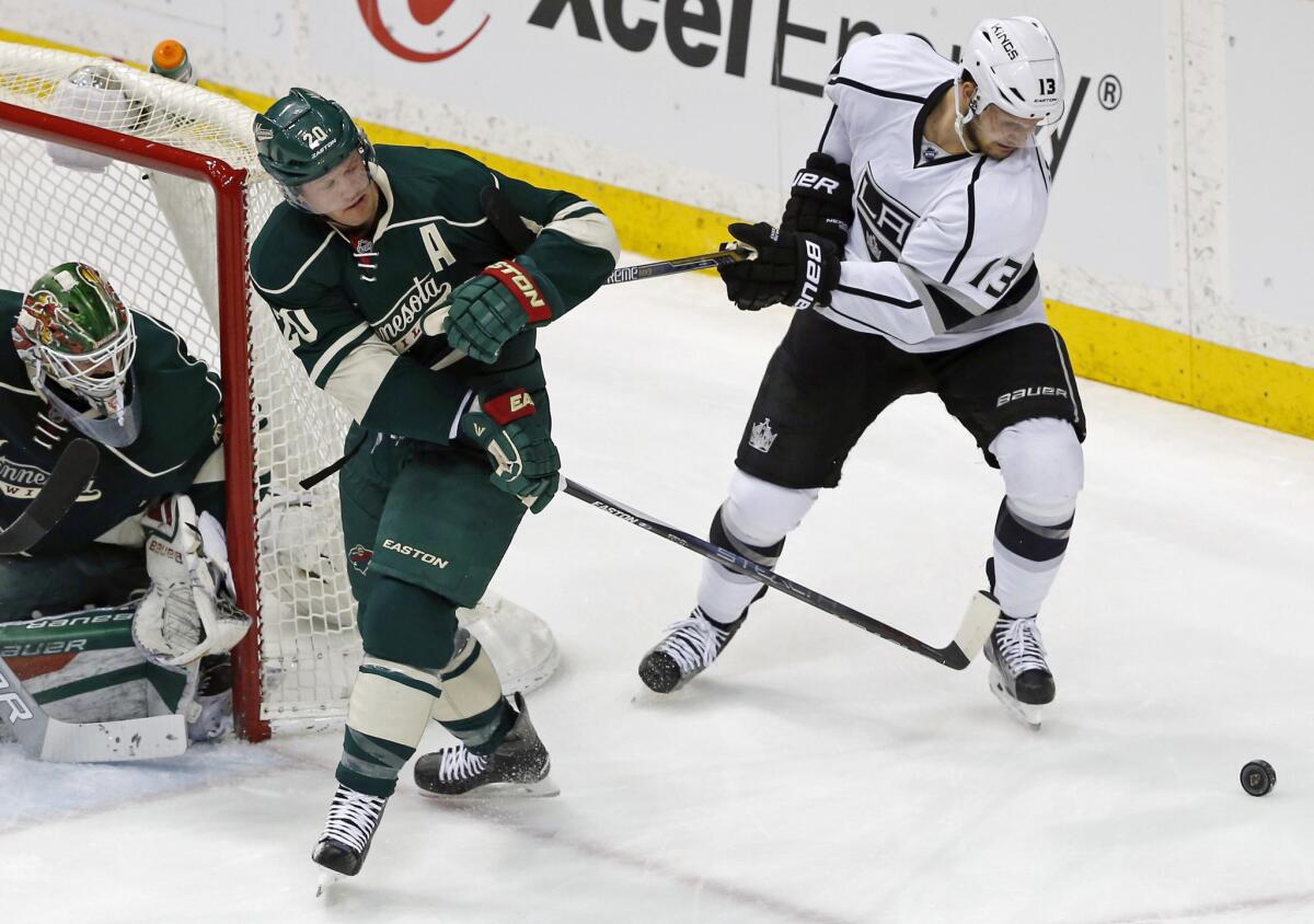 Kings forward Kyle Clifford, right, tries to free his stick from Wild defenseman Ryan Suter as goalie Devan Dubnyk looks on during the first period of a game on March 22.
