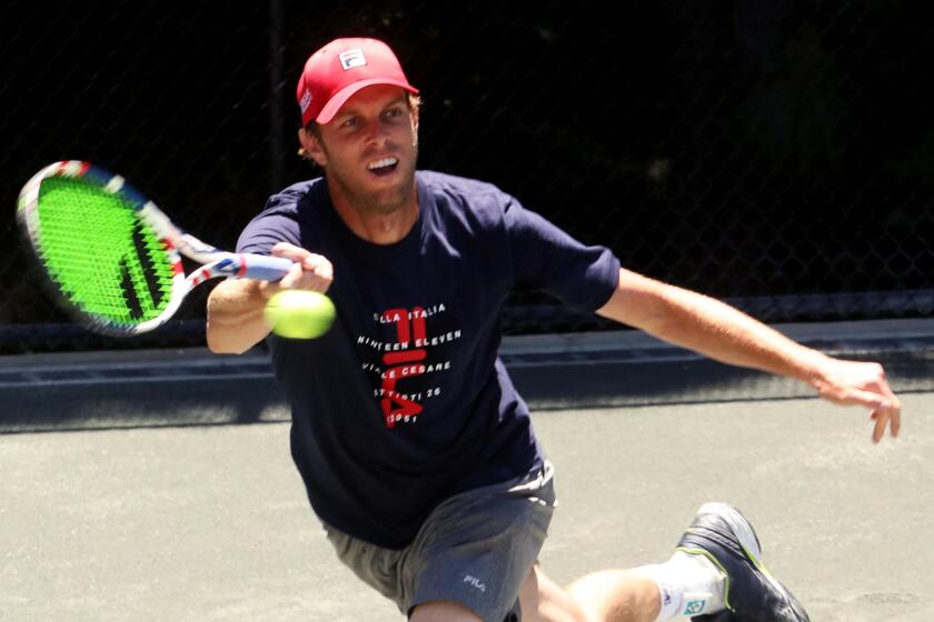 ROLLING HILLS, CA - MAY 17, 2020 - - Sam Querrey, returns a shot from Brandon Holt during the final round of the Homecourt Advantage Tennis Tournament in Rolling Hills, California, on May 17, 2020. Querrey went on to win the tournament. The event was played on a clay court in the backyard of tennis fan Scott Douglas. A few friends a family watched the competition. Before being allowed into the event a doctor was on hand to check visitors and ask if they had a fever or had been exposed to anyone with Covid-19. (Genaro Molina / Los Angeles Times)