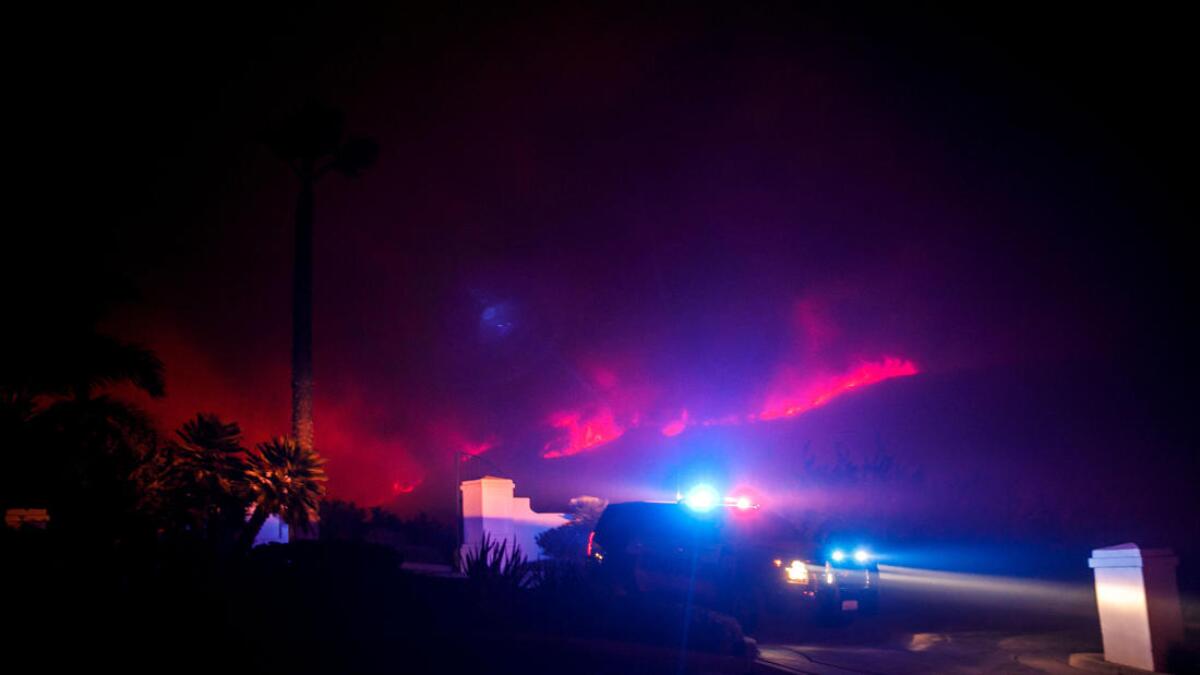 Law enforcement vehicles patrol a neighborhood in a mandatory evacuation area on Dec. 5 in Ventura.