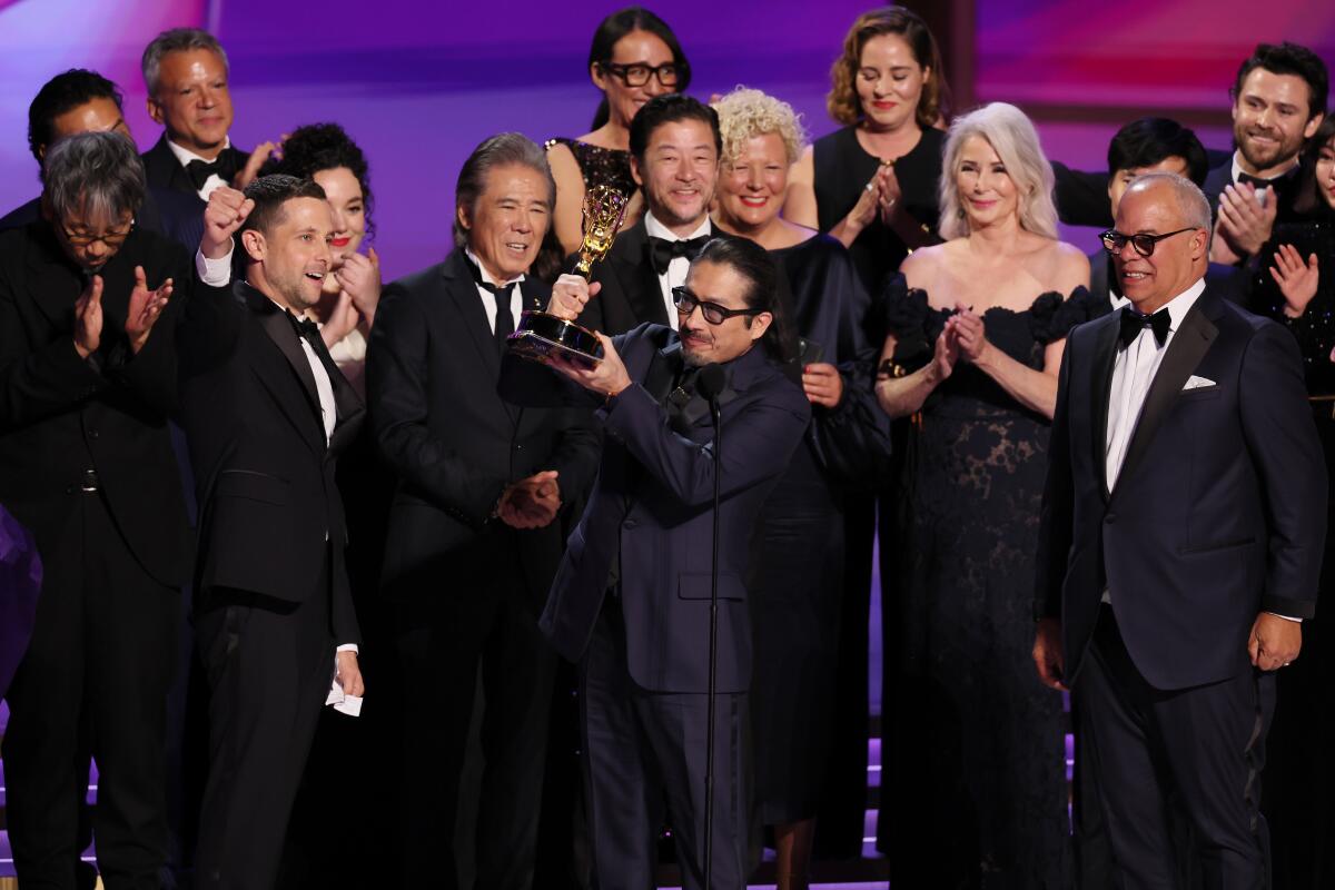 a group of people in formal wear onstage with an Emmy