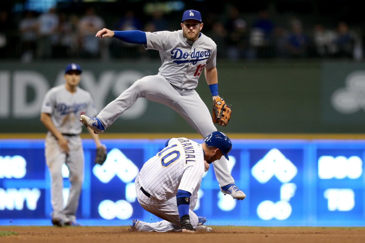 Dodgers' Max Muncy turns a double play over Milwaukee Brewers baserunner Yasmani Grandal during the sixth inning of Friday's win.