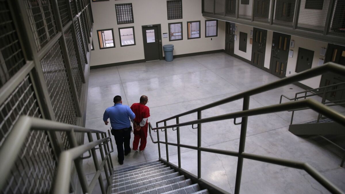 A guard escorts an immigrant detainee at the Adelanto ICE Processing Center in 2013.