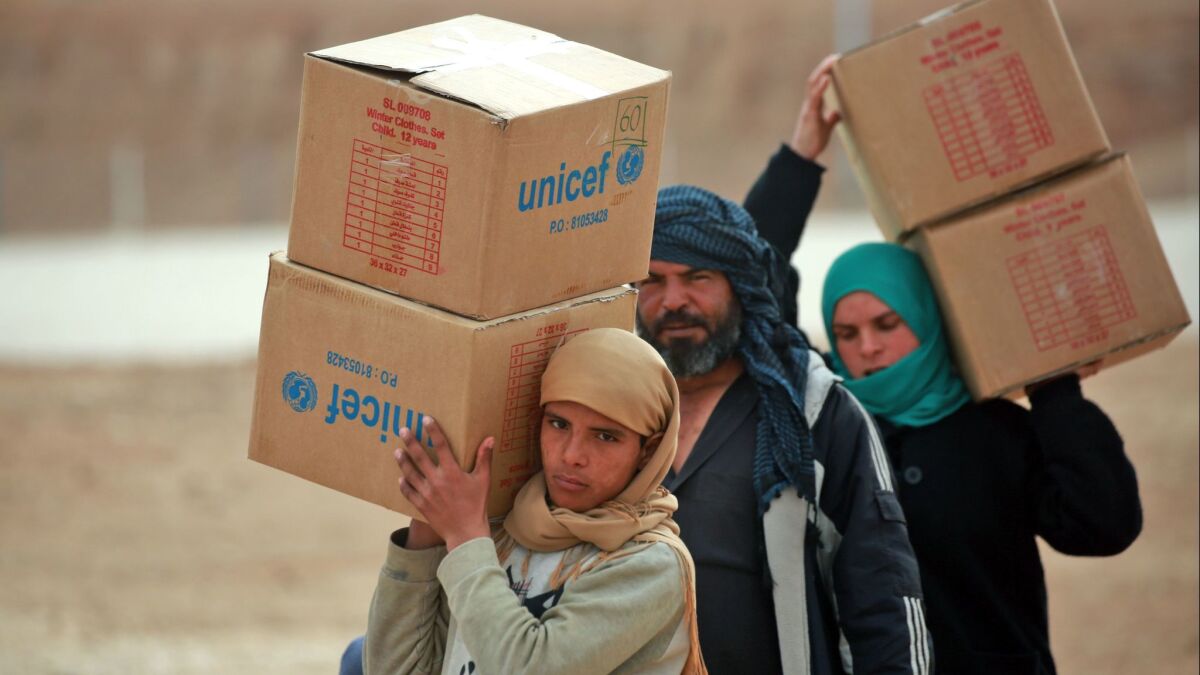 Displaced Syrians, who fled their homes in the city of Dair Alzour, carry boxes of humanitarian aid supplied by the United Nations Children's Fund at a refugee camp in Syria's northeastern Hassakeh province.