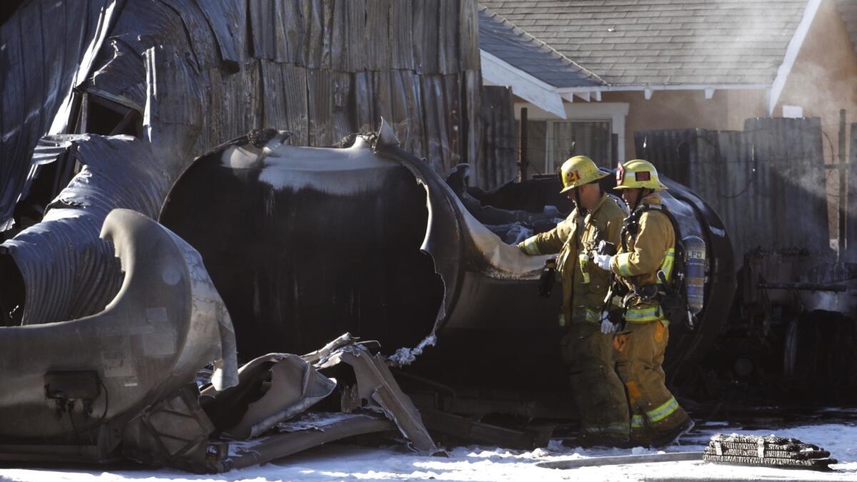 Firefighters look over a tank that exploded in the 200 block of West Slauson Avenue on Sunday morning. A tanker in a yard exploded, causing a fire to a nearby home and injuring two occupants.
