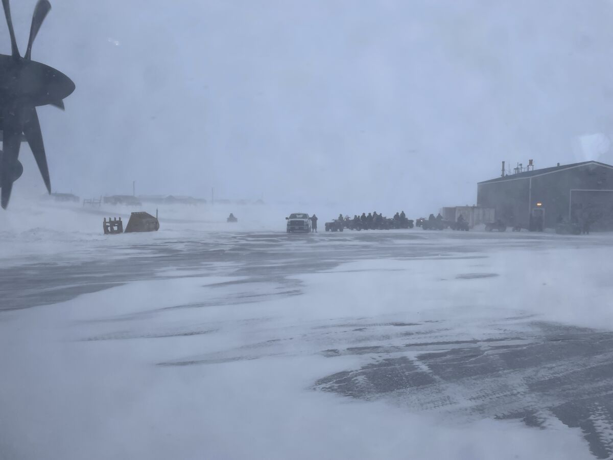 This March 28, 2023, photo shows townspeople in Gambell, Alaska, waiting in a snowstorm on four-wheelers to transport Alaska National Guard personnel from the air strip to the school for a ceremony. Sixteen Alaska National Guard members were honored for helping rescue the 11 crew members of a Navy plane that was shot down in 1955 by Soviet jet fighters and crash-landed about 8 miles from Gambell, on St. Lawrence Island, and 15 medals were presented posthumously. (AP Photo/Mark Thiessen)
