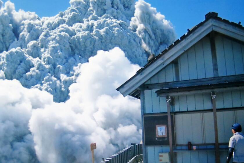 In this photo taken Sept. 27, 2014 by 59-year-old hiker Izumi Noguchi one of at least 47 who fell victim to the eruption of Mount Ontake, a hiker watches dense plumes of gases and ash gushing out from the summit crater as the volcanic mountain starts to erupt.