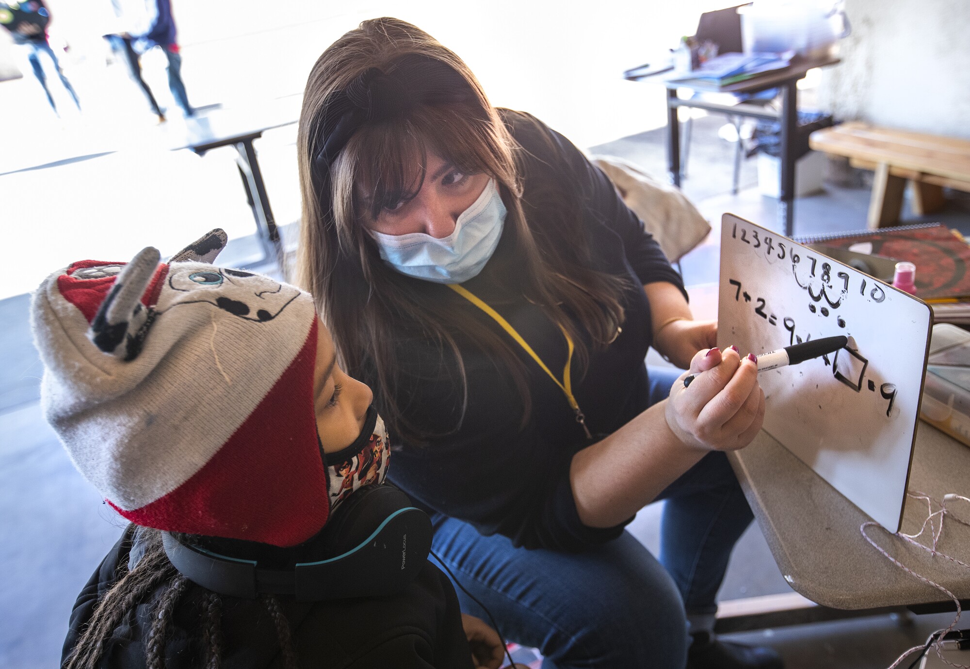 Volunteer Elyse Stelford teaches math to a 6 year old 1st grader at a learning pod for homeless children,