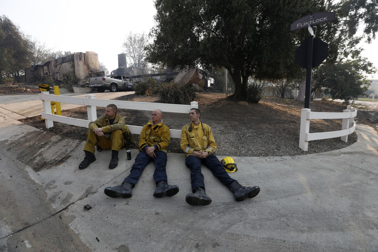 Los Angeles firefighters Ryan Miller, left, Justin Randolph and Kobe Sallstrom grab some brief rest at the corner of Flintlock Lane and Silver Spur Lane in Bell Canyon on Saturday.