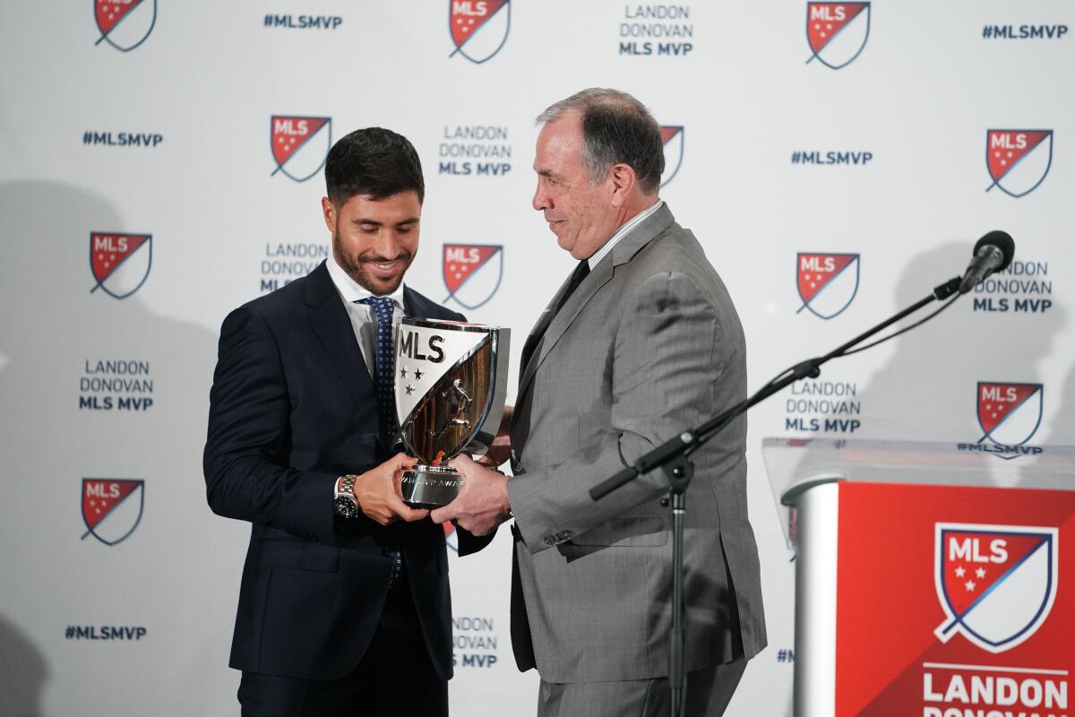 Bruce Arena (der.) entrega el trofeo de Jugador Más Valioso a Carles Gil.