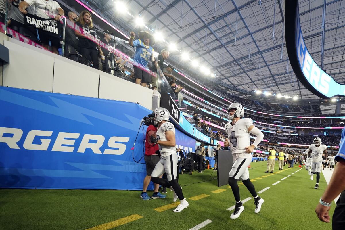 Las Vegas Raiders quarterback Derek Carr and other players leave the field.