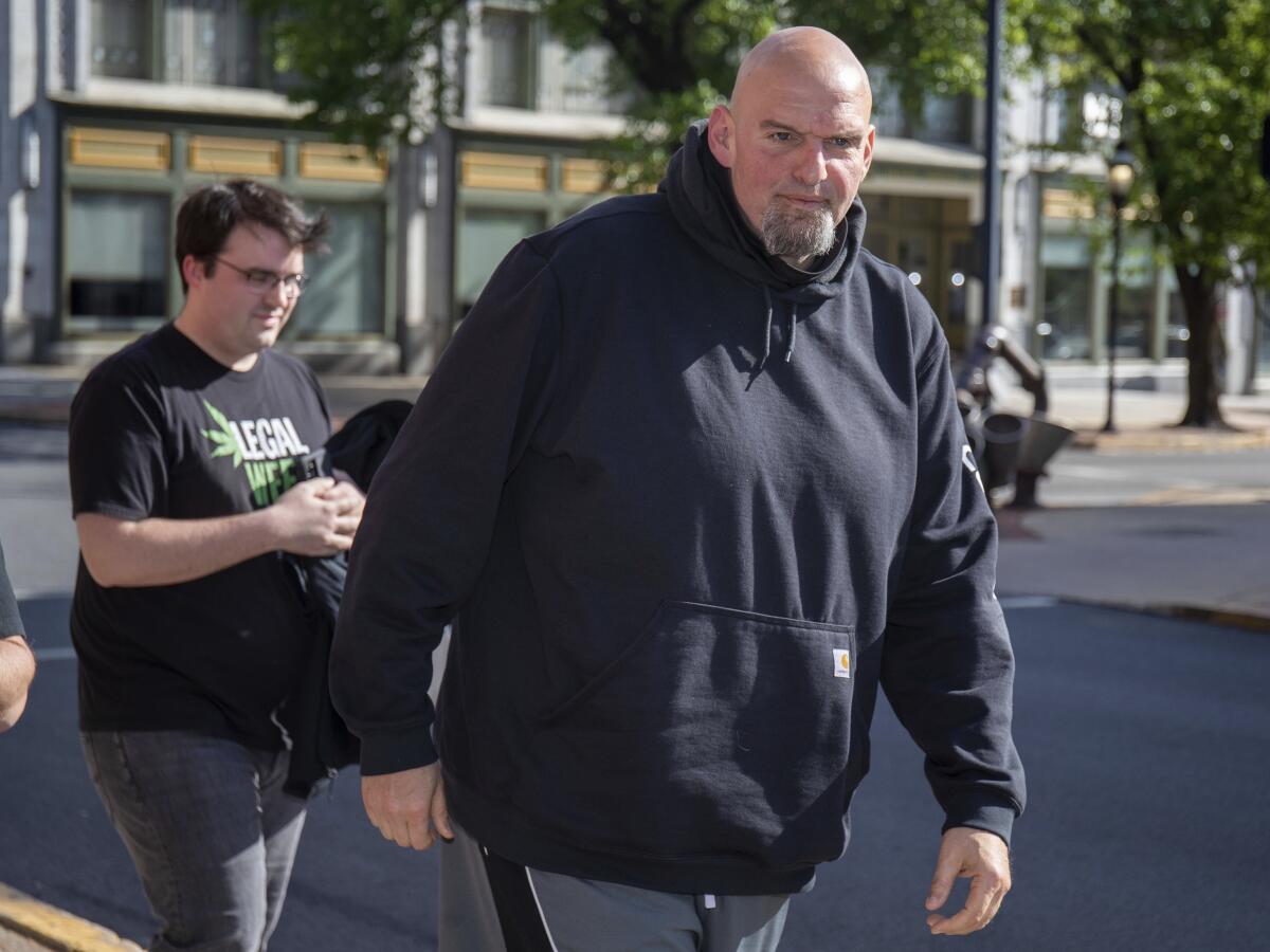 John Fetterman wears a hoodie as he walks down a street