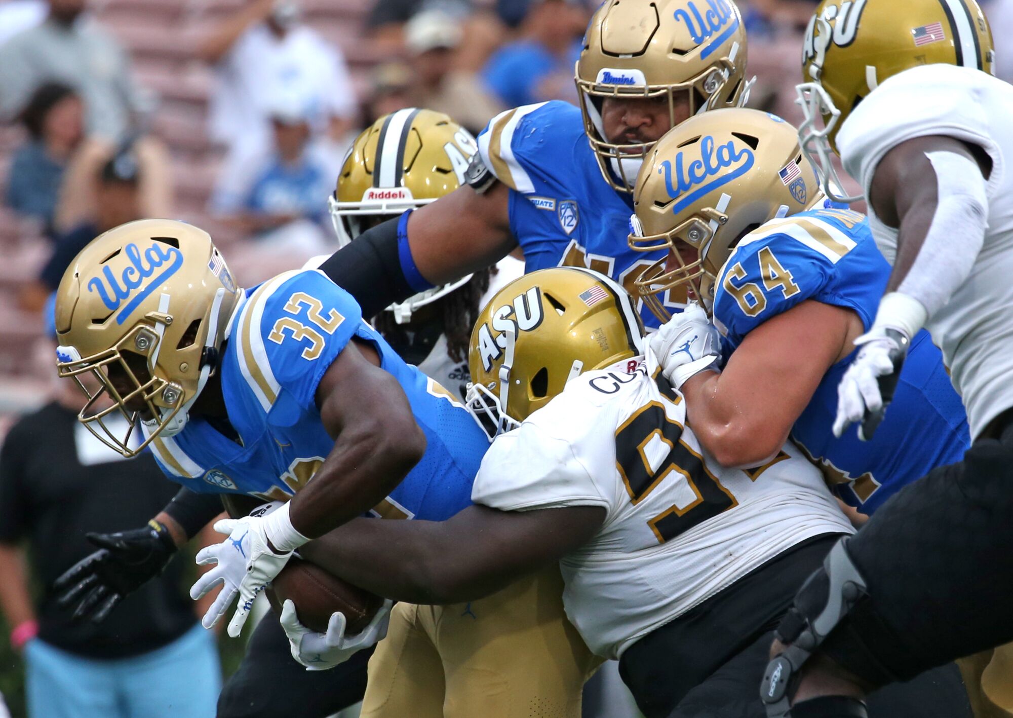 UCLA's Christian Grubb hangs on to the ball as other players pile on.