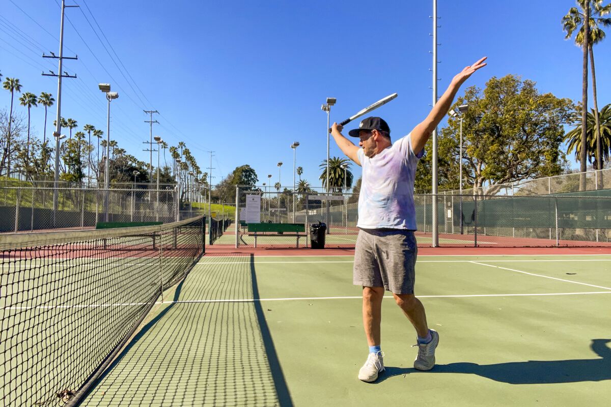 A man cheers near the net on a green tennis court