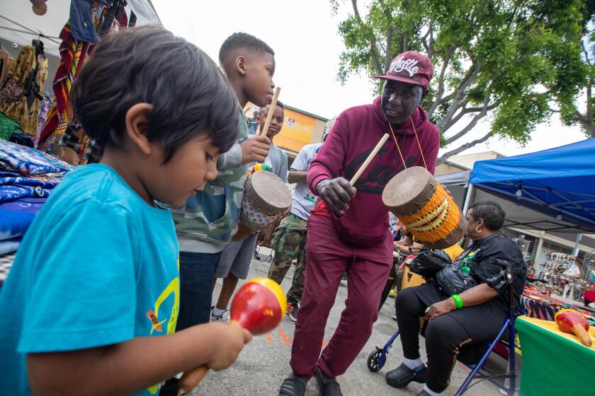 Leimert Park, CA - June 19: Pop Diouf, right, drums along with kids as people gather at the Leimert Park Village Juneteenth Festival to enjoy food art and music on Monday, June 19, 2023 in Leimert Park, CA. (Brian van der Brug / Los Angeles Times)