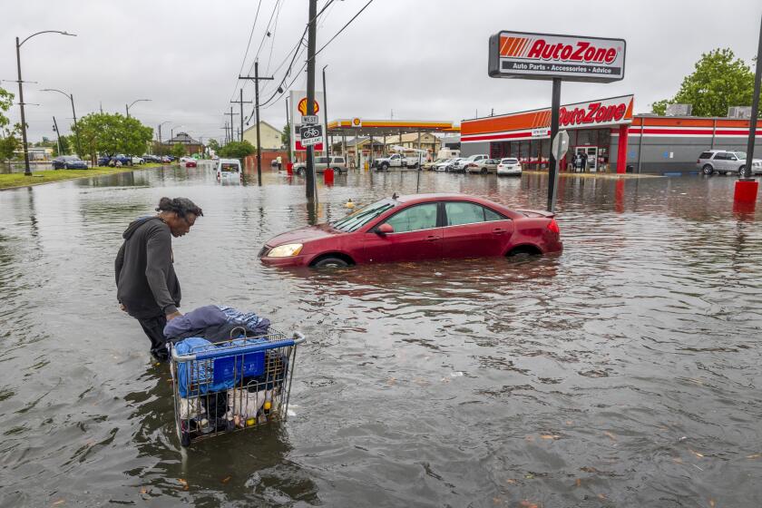 People carry their belongings down a flooded Broad Street in New Orleans, during a severe rainstorm on Wednesday, April 10, 2024. (Chris Granger/The Times-Picayune/The New Orleans Advocate via AP)