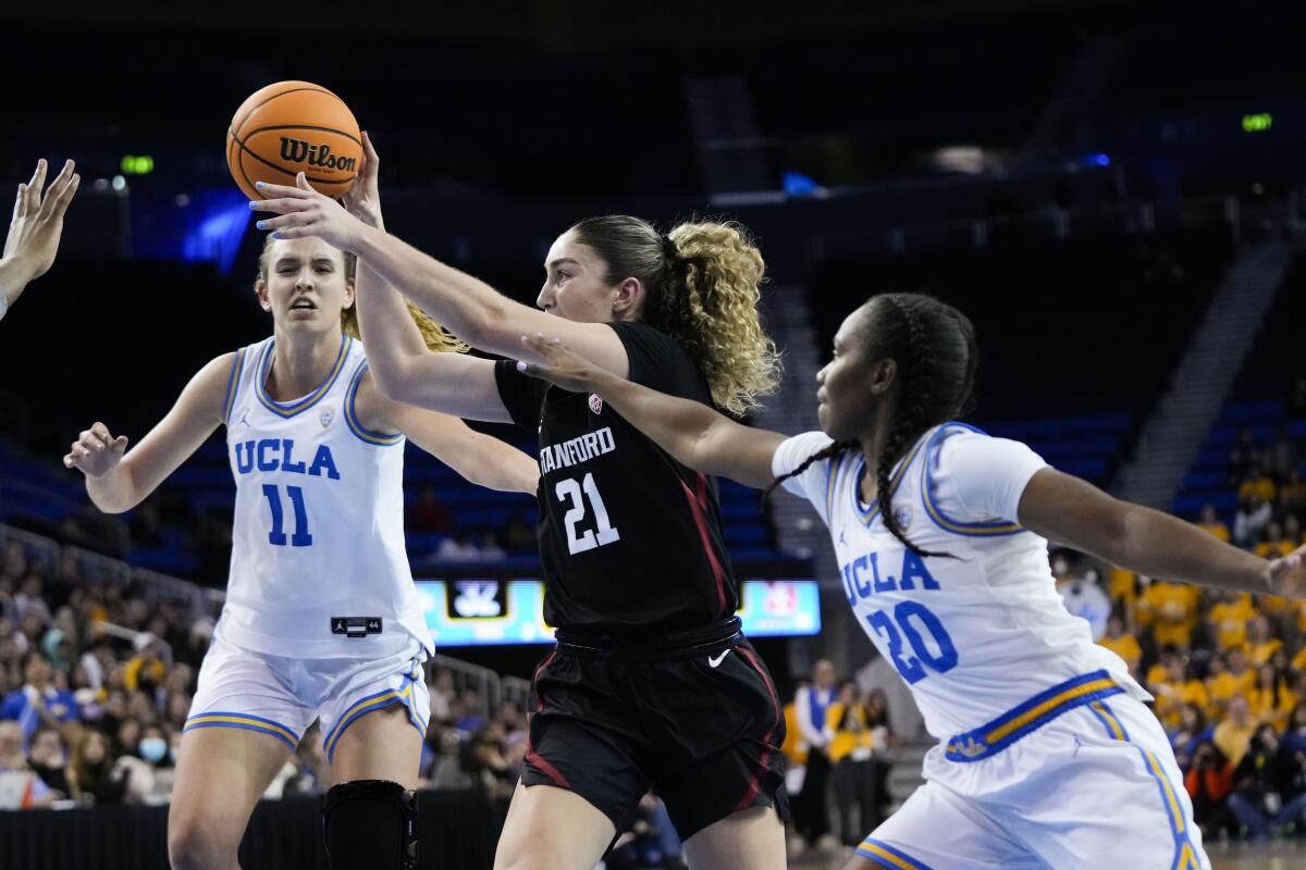 Stanford forward Brooke Demetre passes the ball as UCLA guard Charisma Osborne and forward Emily Bessoir defend.
